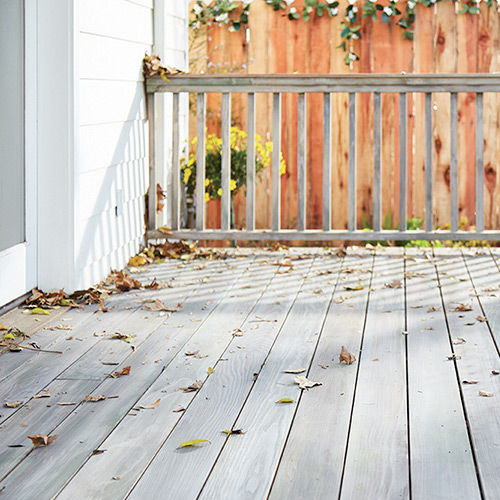 Grey stained deck with leaves on it in the Fall