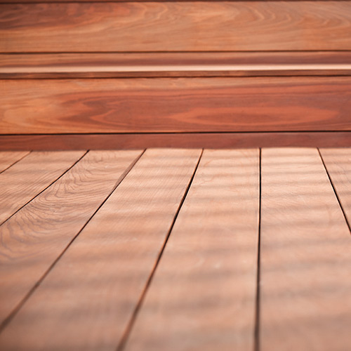 Close-up photo of stain wooden flooring next to the baseboards